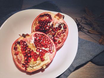 High angle view of halved pomegranate in plate on table