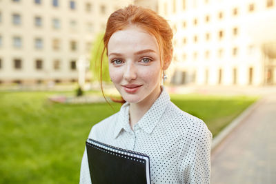 Portrait of smiling young woman standing in campus