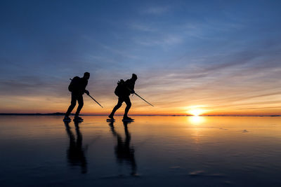 People long-distance skating at sunset, vanern, sweden