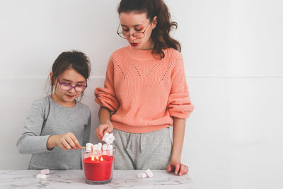 Two girls roast marshmallows over a candle fire.