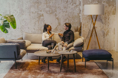 Businesswoman communicating with male colleague while sitting on couch during event at convention center