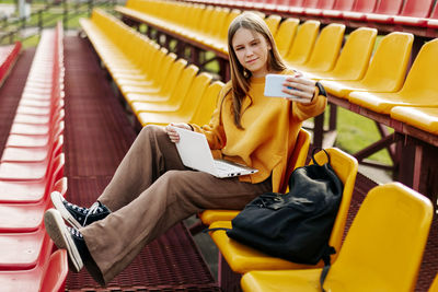 A girl on the seats in the school stands takes a selfie and prepares for classes