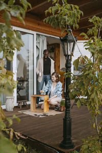 Happy couple helping each other while painting furniture on porch