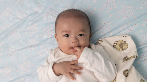 Portrait of cute baby girl lying on bed at home