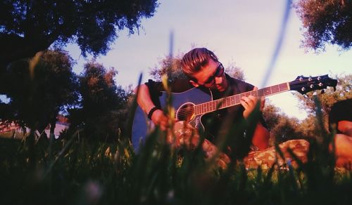 Man playing guitar against trees