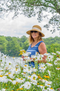 Smiling woman in hat standing by flowers