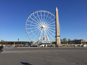 Architectural column and ferris wheel against clear blue sky