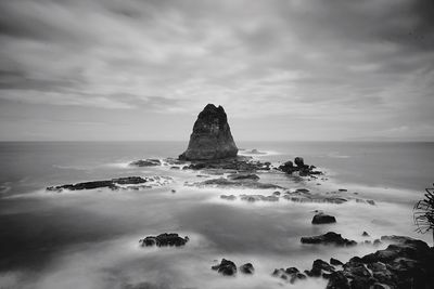 Scenic view of rock formation in sea against sky