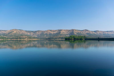 Scenic view of lake and mountains against clear blue sky