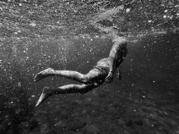 Low section of shirtless man swimming in sea