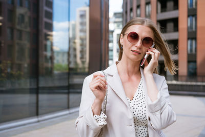 Business woman with phone near office. portrait of beautiful smiling girl