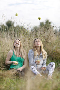 Smiling friends juggling balls on field