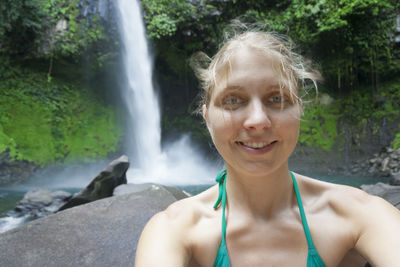 Portrait of young woman against waterfall
