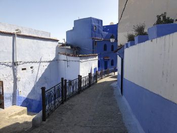 Footpath amidst buildings against blue sky