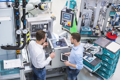 Two men with tablet talking in factory shop floor