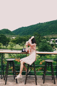 Woman sitting on chair at table against clear sky