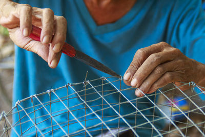 Midsection of person making cage