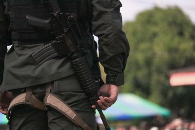 Rear view of man with rifle standing outdoors