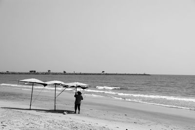 Man on beach against clear sky