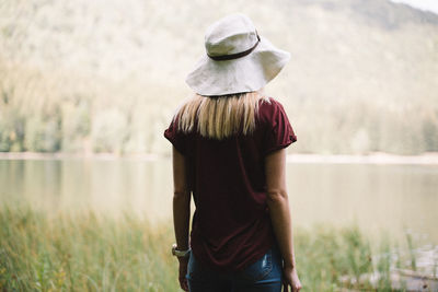 Rear view of woman standing by lake against sky