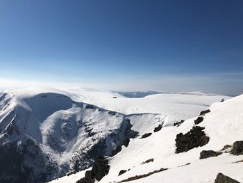 Scenic view of snow covered mountains against blue sky