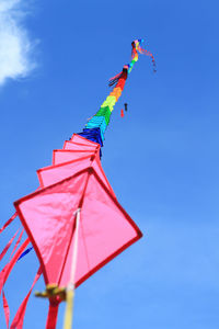 Low angle view of kites flying in blue sky