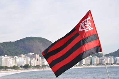 Scenic view of flag by sea against sky