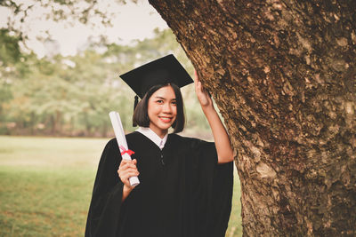 Young woman in graduation gown holding certificate