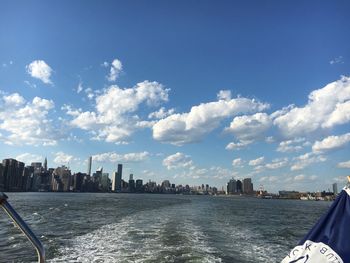 City at waterfront against cloudy sky