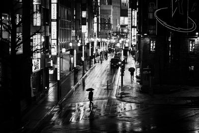 People walking on wet street in city at night