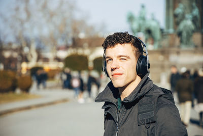 Young man listening music on street in city
