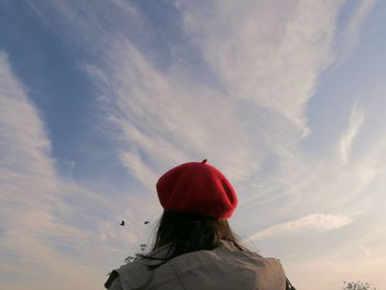 Rear view of woman with red umbrella against sky