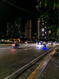 Cars on illuminated street by buildings at night