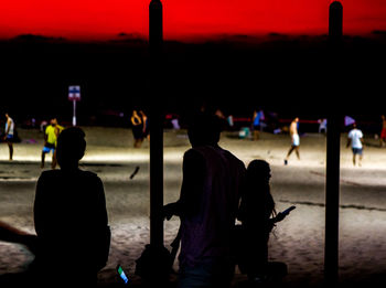 Silhouette people standing on illuminated street at night