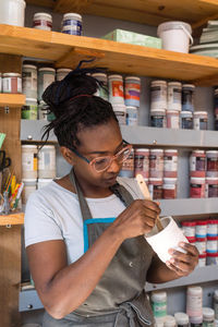 Female small business owner painting a cup at her art ceramic studio 