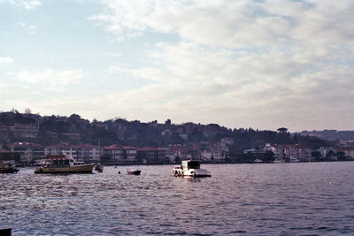 Sailboats in sea against sky in city