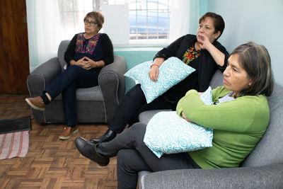 Business colleagues stacking hands while sitting on sofa at home