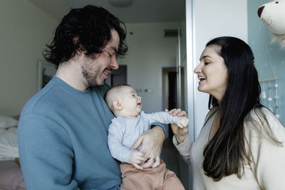 Happy father and mother playing with baby boy at home