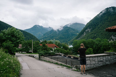 Rear view of woman standing on mountain against sky