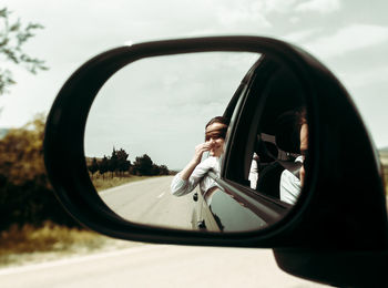 Reflection of woman in car on side-view mirror