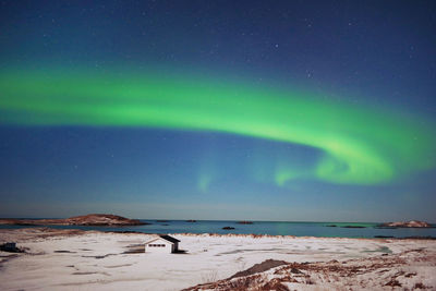 Stunning dancing northern lights over snowy mountains and sea coast in lofoten islands, norway.  