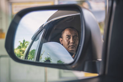 Reflection of man on side-view mirror of car