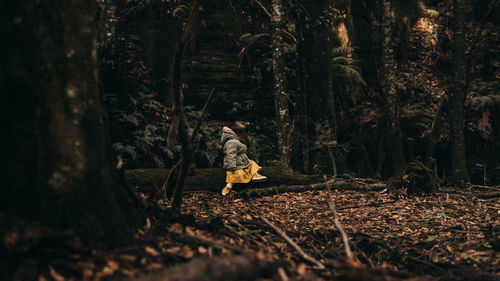 Rear view of man standing by trees in forest