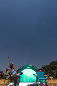 Man sitting against blue sky at night