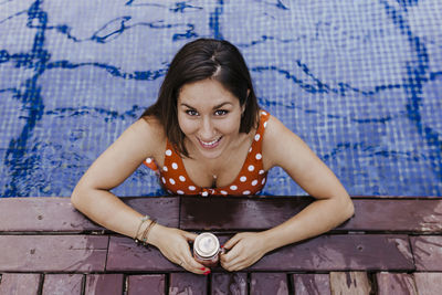 Portrait of a smiling young woman sitting against wall