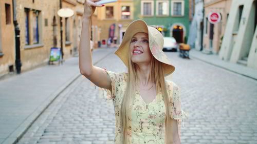 Portrait of smiling young woman standing on street in city