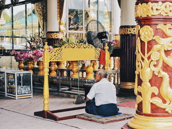 Rear view of woman sitting in temple outside building