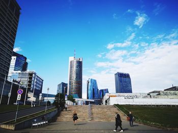 People on modern buildings in city against sky