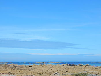 Rocks by sea against blue sky