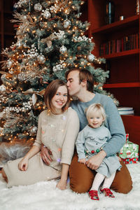 Portrait of cheerful family sitting by christmas tree